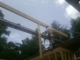 Carpenter setting a ridge beam over a new addition frame in Stone Mountain
