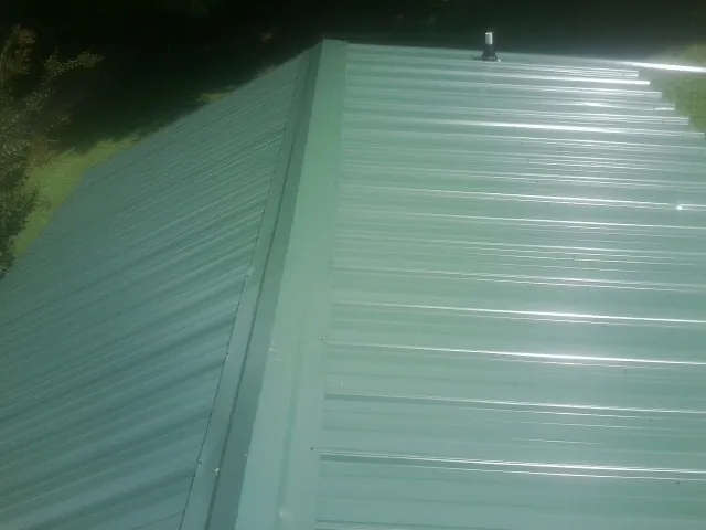 New green metal panels meeting at the ridge of a roof — Flat Roof Repair work by our crew in Stone Mountain