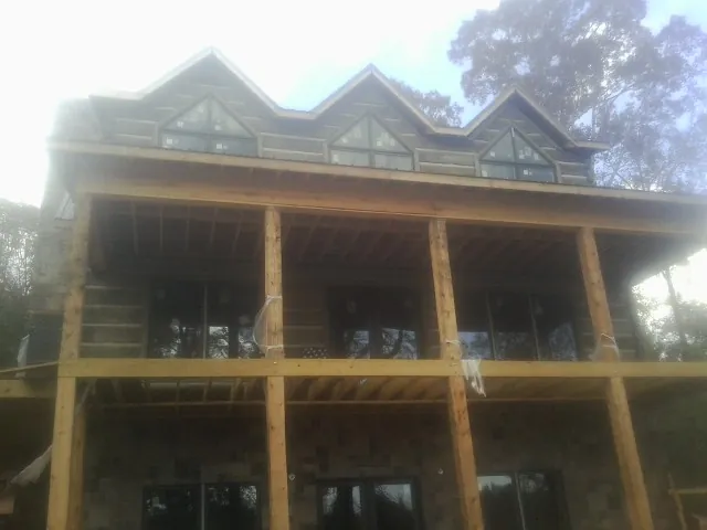 Dormers and porch framing on a large log home under construction — Roof Coating work by our crew in Stone Mountain