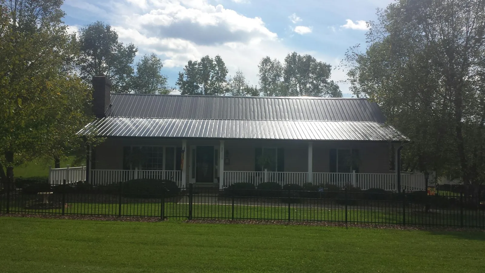 Gray metal roof on a brick ranch with a full width front porch — Gutter Guard Installation work by our crew in Stone Mountain