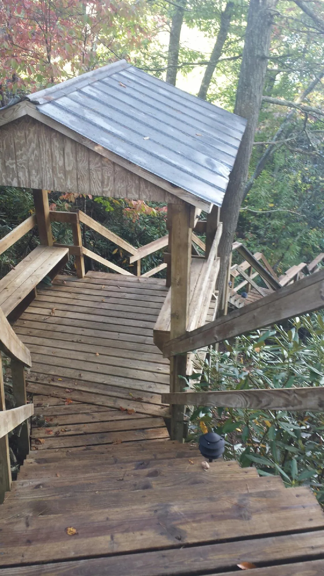 Metal roofed shelter over wooden steps on a wooded walkway — Skylight Repair & Installation work by our crew in Stone Mountain